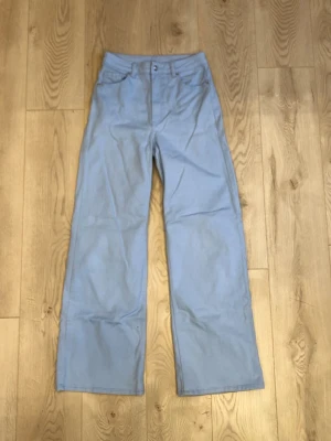 Ljusblåa vida jeans - Ljusblå jeans med vida ben och hög midja. Klassisk femficksmodell med bälteshällor och knappgylf. Materialet känns mjukt och bekvämt. 