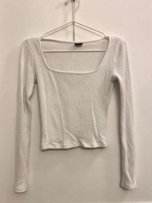 Vit ribbad topp från Gina Tricot - Säljer en vit ribbad långärmad topp från Gina Tricot. Toppen har en fyrkantig urringning.