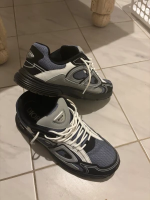 B30 sneakers i blå och svart - Snygga B30 sneakers i blått, svart och vitt med coola detaljer. Ovandelen är i mesh och läder med vita skosnören och robust svart sula. Perfekta för dig som gillar exklusiva och trendiga sneakers med sportig vibe.