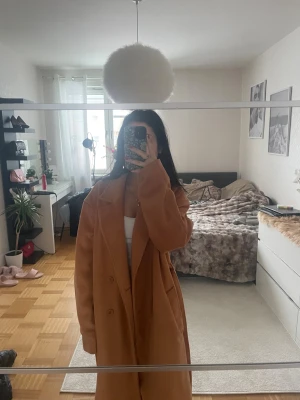 Beige kappa från NA-KD med bälte - Säljer en snygg beige kappa från NA-KD med klassisk krage, knappar framtill och matchande bälte i midjan med storlek 38 och den är lite för stor för mig. Lång modell med raka ärmar och stilren look, perfekt för dig som vill ha en trendig och tidlös jacka.