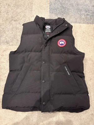 Canada Goose väst  - Väldigt bra skick och har endast en skada på dragkedjan, går dock fortfarande att använda precis som vanligt. Storlek L/G men sitter som Xs-S
