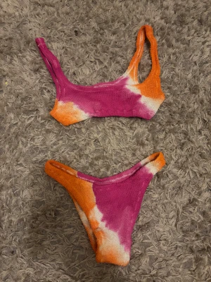 Färgglad bikini från MC2 Saint Barth - Superfin bikini från MC2 Saint Barth i en mix av rosa, orange och vitt. Bikinin har en cool tie-dye look och är gjord i ett ribbat, stretchigt syntetmaterial. Storlek S