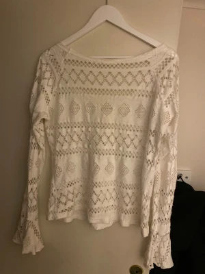 Vit spetsblus från B.Young - Säljer en vit långärmad blus från B.Young med v-ringning med spetsmönster. Blusen har utsvängda ärmslut och ett snyggt geometriskt mönster i tyget. Storlek L men passar mer som M
