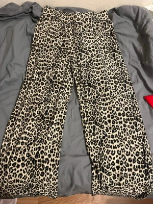 Leopardmönstrade wide byxor M - Säljer ett par sjukt snygga wide byxor från The Black Label Collection i storlek M. De har ett leopardmönster i beige och svart, med hög midja och mjukt bomullsmaterial. Perfekta för dig som vill sticka ut och köra på en bold look.