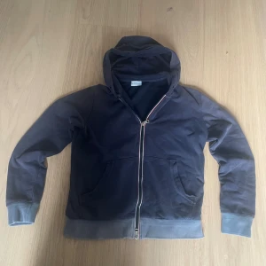 Mörkblå hoodie från Moncler med dragkedja - Mörkblå hoodie från Moncler med klassisk logga på ärmen, huva och hel dragkedja framtill. Tröjan har ribbade muddar och fickor på magen. Tillverkad i mjuk bomull som är skön att ha på sig. Perfekt för chill dagar eller när du vill ha en clean look. Tröjan är lite sliten men inga hål, bild 3 