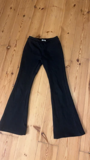 Svarta bootcut byxor från Kappahl - Svarta byxor från Kappahl i storlek 164. De har en snygg bootcut-passform med utsvängda ben och är tillverkade i ett mjukt material som känns skönt mot huden. Perfekta för dig som gillar en klassisk och stilren look.
