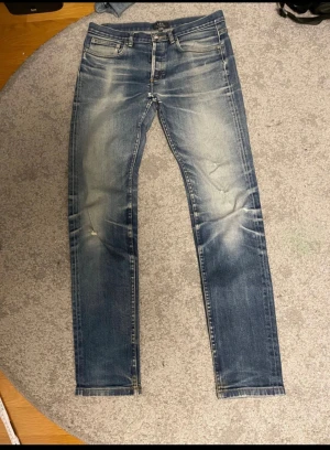 A.P.C. Slim jeans i blå tvätt - Snygga slim jeans från A.P.C. i klassisk blå tvätt med slitningar och ljusa partier. Modellen har fem fickor, knappgylf och smal passform. Materialet är 98% bomull och 2% polyuretan för lite stretch. Perfekt för dig som gillar en modern och slimmad look.