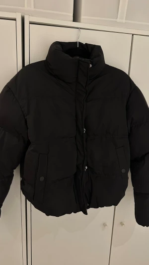 Svart pufferjacka med hög krage - Säljer en svart pufferjacka med hög krage, från New Yorker i storlek s