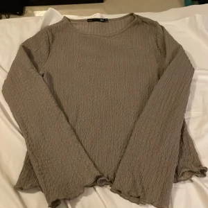 Mullvads brun långärmad topp från 157 - Säljer en brun långärmad topp från 157 i storlek M. Toppen har ett crinklat, strukturerat tyg och lätt vågiga kanter vid ärmslut och nederkant. Den har rund halsringning och loose passform, perfekt för dig som gillar chill och enkel stil.Passar till de som har S med.