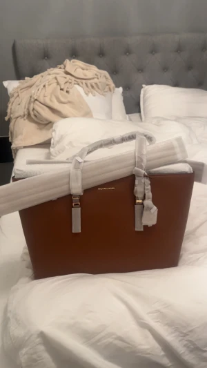 Brun handväska från Michael Kors - Snygg tote/handväska från Michael Kors i en klassisk brun färg, helt ny och äkta! Säljer eftersom den aldrig kom till andvänding❤️