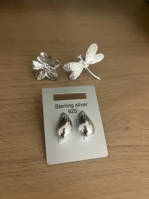 Tre silversmycken – ringar & örhängen - Säljer dessa ringar och örhängen, aldrig använt då jag är en guldtjej, en ring som är en blomma och andra ringen som är en trollslända❤️