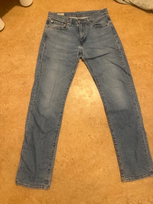 Levi's 514 ljusblå jeans W31 L34 - Säljer ett par Levi's 514 jeans i ljusblå tvätt med klassisk femficksdesign och raka ben. Jeansen har normal passform och är tillverkade i slitstarkt bomullsjeansmaterial. Perfekt för dig som gillar en tidlös och clean look.köpte för 900kr och säljer för 500kr(pris kan diskuteras)