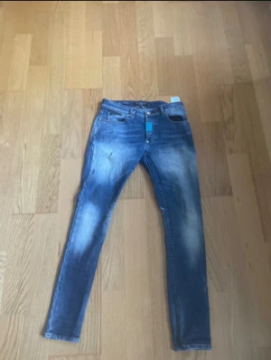 Philipp Plein jeans  - Snygga blå jeans från Philipp Plein med super straight cut och coola slitningar. Klassisk femficksmodell med metallknapp med logga och röda sömmar på insidan. Jeansen har en tvättad look och är tillverkade i premium denim.