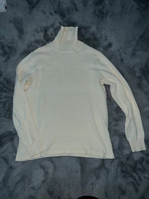 Vit polotröja från Black Rebel  - Funkar även S. Tröjan har ett diskret strukturerat mönster med breda ränder och ribbad polokrage. Långärmad och tillverkad i mjuk stickad bomull som känns skön mot huden. Perfekt för dig som gillar stilrena och enkla plagg.