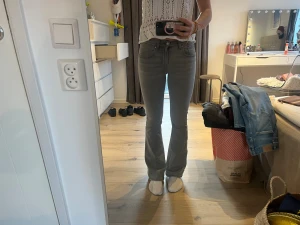 Grå bootcut jeans från Gina tricot strl 34 - Snygga grå jeans från Gina tricot i storlek 34. Modellen har bootcut-ben, klassisk femficksdesign och normal midja. Jeansen är tillverkade i mjukt denimtyg med lite stretch för skön passform. Perfekt för dig som gillar en stilren och avslappnad look.