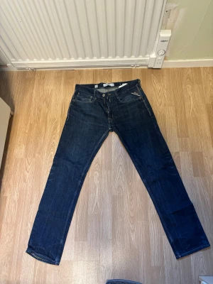 Replay Rocco blåa jeans  - Snygga Replay Rocco  jeans i mörkblå tvätt med klassisk femficksdesign och raka ben. Jeansen har en normal passform och är tillverkade i slitstarkt denim med subtila kontrastsömmar. Perfekt för dig som gillar en enkel och stilren look.