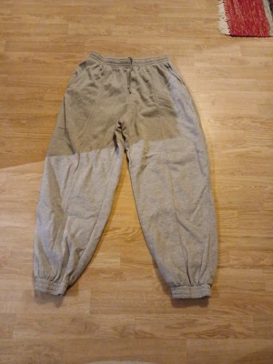 Grå mjukisbyxor i storlek S - Säljer ett par grå mjukisbyxor i storlek S med resår i midjan och vid bensluten. Byxorna har en loose passform och är tillverkade i mjukt bomullsmaterial. Perfekta för chill dagar eller när du vill vara extra bekväm.