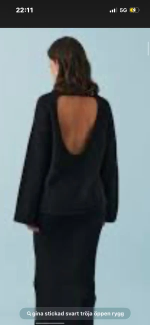 Svart stickad tröja med öppen rygg - Svart stickad tröja från Gina med en stor, snyggt öppen rygg. Tröjan har långärmade ärmar och en loose passform som ger en chill vibe. Perfekt för dig som vill ha något enkelt men ändå med en cool detalj.