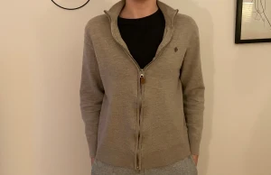 Beige kofta med dragkedja från Morris - Snygg beige kofta från Morris med ribbad krage och hel dragkedja framtill. Tröjan har långärmad passform och är tillverkad i mjuk bomull. Diskret Morris-logga broderad på bröstet. Perfekt för chill dagar och enkel att matcha med jeans eller mjukis.