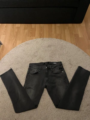 Replay svarta skinny jeans - Svarta Replay jeans i skinny fit med slitningar på benen och klassiska fem fickor. Snygga detaljer på bakfickorna och diskret Replay-logga. Jeansen har en smal passform och är tillverkade i stretchigt jeanstyg för extra komfort.