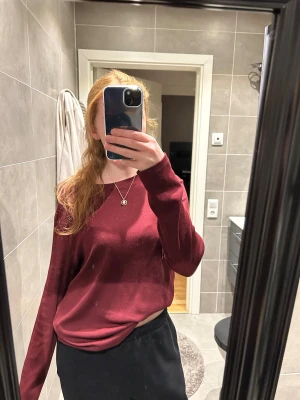 Mörkröd långärmad tröja - Enkel och stilren mörkröd långärmad tröja med rund halsringning. Tröjan har en loose passform och är tillverkad i ett mjukt, tunt material som känns skönt mot huden. Perfekt att matcha med både jeans och kostymbyxor.