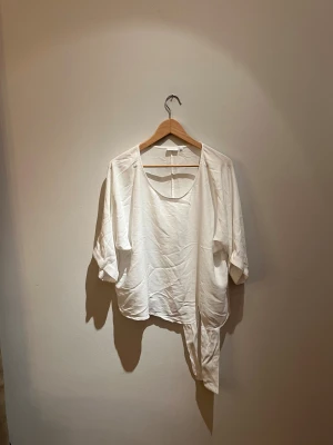 Vit blus från YAYA Women - Säljer en vit blus från YAYA Women i storlek 38. Blusen har en lös passform, trekvartsärmar och snygga detaljer med knyt framtill. Materialet är mjukt och lätt, perfekt för en chill och stilren look. Rund halsringning och enkel design gör den lätt att matcha.