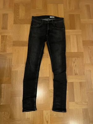 Svarta slim jeans från Tiger of Sweden - Svarta jeans från Tiger of Sweden i modellen Roadie, slim fit med klassisk femficksdesign. Jeansen har en snygg mörk tvätt och raka ben med smal passform. Materialet är mjukt och stretchigt jeans, perfekt för dig som gillar stilrena och moderna byxor. Kom med frågor och bud!