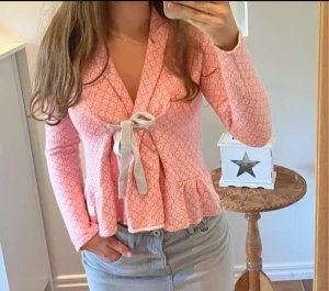 Rosa mönstrad blus från Odd Molly - Superfin rosa blus från Odd Molly med vitt geometriskt mönster, volang nertill och snygg knytning framtill i ljusgrått. Långärmad och med mjukt bomullsmaterial som känns skönt mot huden. Perfekt för dig som gillar detaljer och vill sticka ut lite extra. Passar xs-S 🩷