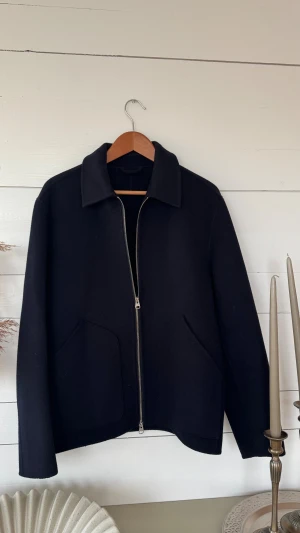  ulljacka från ARKET - Jacka från ARKET. Jackan har två stora fickor framtill och en silverfärgad dragkedja. Materialet är mjuk ull som värmer bra. Har endast används ett fåtal gånger, ser ut som ny. Nypris: 2590kr Säljs för: 599kr och är förtillfället slutsåld på Arket. 