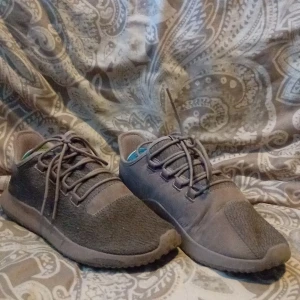 Beiga adidas sneakers med snörning - Snygga beiga adidas sneakers med rund tå och platt sula. Skorna har en stilren design med ovandel i textil och mocka, samt klassisk snörning. Perfekta för dig som gillar en enkel och clean look till vardags.