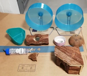 Bomaterial med mat till hamstrar - 2 st. gnagarhus i björk, 1 st. Tunnel för hamster 15 cm, 1 st. mini hamsterskål för mat, 1 st. Hörntoalett för smådjur, hamstertoalett, 1 st. Hamster vattenflaska, 2 st. Hamster rullbollar “Runner Hamster” varav en på bilden (inne i buren) medan den andra är likadana och finns inte med på bilder, Maten för hamstern(rar) i 2 påsar, samt 1 påse tilläggsmat av torramaskarr; plus en vaddpåse!2 st. Spån 2–2,5 kg/vikt som säljs SEPARAT från annat tillbehör - 50 kr/st, alltså, 100kr.