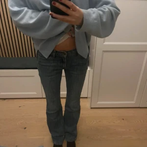 Blå bootcut jeans från Brandy Melville  - Säljer ett par klassiska blå jeans från brandy med bootcut passform. Jeansen har låg midja och raka ben med lätt utsvängning nedtill. Materialet är slitstarkt denim och färgen är en snygg mellanblå ton med subtila vertikala ränder.