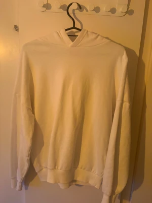 Vit hoodie från Bekkin med huva - Vit hoodie från Bekkin i storlek 158/164 cm, passar dig som är 13-14 år. Tröjan har en klassisk huva och ribbade muddar vid ärmslut och nederkant. Perfekt för chill dagar och enkel att matcha med jeans eller mjukisbyxor.