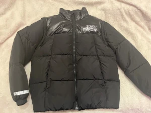 Ny Svart pufferjacka från Lindex - Säljer en helt ny, aldrig använd,  svart pufferjacka från Lindex med hög krage och reflekterande detalj på ärmen. Säljes då sonen plötsligt växte över 1 dm i somras. Storlek 164.    200kr eller bud