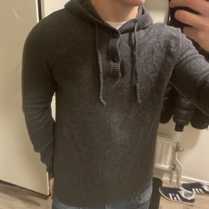 Grå stickad hoodie - Väldigt snygg och skön grå stickad hoodie. Perfekt nu till kallare väder. Passar S-M. Modellen är 180cm, 73kg.