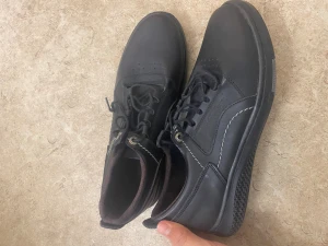 Svarta Timberland sneakers i skinn - Säljer ett par svarta sneakers från Timberland med snygga kontrastsömmar och rund tå. Skorna har snörning och är tillverkade i skinn med en platt, mönstrad sula som ger bra grepp. Perfekta för dig som gillar stilrena och klassiska sneakers.