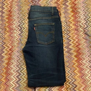 Levi's 512 mörkblå jeans tapered fit - Snygga Levi's 512 jeans i mörkblå tvätt med klassiska fem fickor och gul kontrastsöm. Modellen har tapered fit och normal passform, med knapp och dragkedja fram. Perfekt för dig som gillar stilrena och tidlösa jeans med lite smalare ben.