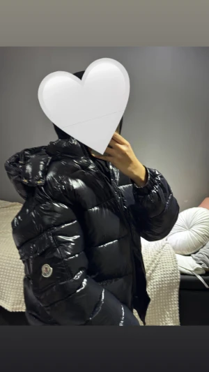 Svart pufferjacka Moncler  - Säljer en svart, glansig pufferjacka Moncler i storlek S men den känns som M. Jackan har huva, dragkedja framtill och Moncler-logga på ärmen. Helt ny endast provat för bilden. Skriv innan ni beställer. 