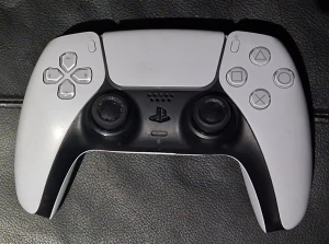 PlayStation 5 DualSense Wireless Controll - Sony DualSense trådlös handkontroll till PlayStation 5. Vit och svart design, responsiva knappar och adaptiva triggers. Viss kosmetisk slitage syns på styrspakar och baksida, men fullt fungerande. Perfekt för gaming med haptisk feedback och inbyggd mikrofon.