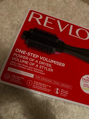 Revlon värmeborste - Revlon One-Step Volumiser är en oval hårborste med svarta borst och rosa detaljer, designad för att ge volym och torka håret samtidigt. Borsten kombinerar funktionerna av en hårtork och en styler, perfekt för att skapa fylligt och stylat hår snabbt. Har endast använt den 2 gånger, säljer den eftersom den inte kommer till användning. Priset kan diskuteras.