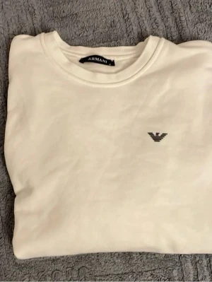 Armani tröja - Snygg vit t-shirt från Armani med klassisk rund hals och svart logga på bröstet. Enkel och stilren design som passar perfekt till jeans eller shorts. Mjuk bomullskvalitet för skön känsla hela dagen. Pris kan diskuteras. Dm mig för bilder frågor