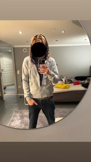 Grå Burberry hoodie med dragkedja - Säljer en grå hoodie från Burberry med klassiskt rutigt foder i huvan och broderad logga på bröstet. Tröjan har dragkedja framtill, snörning vid huvan och två fickor. Perfekt för dig som gillar stilrena och exklusiva streetwear-plagg. Den har ingen fläck och är ren! Storlek M men passa S. Se 4 bild att de saknas 1 silver sak! 