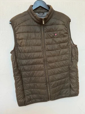 Bondelid dunväst - Säljer en brun dunväst från Bondelid i storlek M. Jag är 188cm och passar också bra till mig. 
