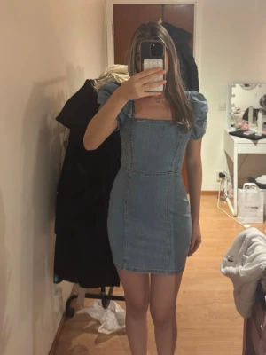 Kort jeansklänning med puffärmar - Säljer en snygg kort jeansklänning med puffärmar och fyrkantig urringning. Passar både XS och S.