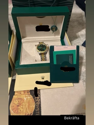Oyster Perpetual Datejust klocka med tillbehör  - Oyster Perpetual Datejust klocka. Automatisk armbandsklocka med datumfunktion. Tvåton stål/guld med jubilee-länk och räfflad bezel. Grön urtavla.  Säljs som fullset och levereras med box, certifikat, kvitto och påse. Klockan är i gott skick och fungerar som den ska. Helt ny, priset kan diskuteras 😁41mm