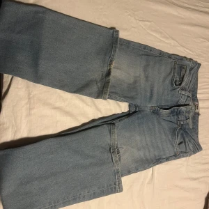 Ljusblå bootcut jeans  - Säljer ett par ljusblå jeans med klassisk femficksdesign och bootcut-ben. Jeansen har normal passform och är tillverkade i mjukt denimtyg. Perfekt för dig som gillar retrovibbar och bredare benslut.