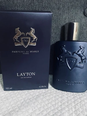 Layton Eau de Parfum 125ml - Lyxig parfym från Parfums de Marly, tillverkad i Frankrike. Volymen är 125 ml. Ingredienser: alkohol denat., parfym, aqua, limonene, benzyl alcohol, linalool, coumarin, citronellol, BHT, citral, geraniol. Perfekt för dig som vill sticka ut med stil.