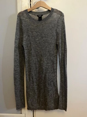 Grå långärmad tröja från Lindex - Säljer en enkel och stilren grå långärmad tröja från Lindex. Tröjan har rund halsringning och är gjord i mjukt, tunt material som sitter skönt mot kroppen. Perfekt att ha som basplagg och lätt att matcha med andra kläder.