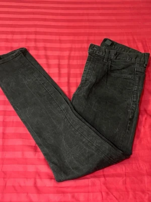 Svarta skinny jeans i stretch - Säljer ett par svarta skinny jeans med lätt tvättad look. Jeansen har klassisk femficksdesign, smal passform och är tillverkade i stretchigt jeansmaterial för extra komfort. Perfekta till sneakers eller boots och funkar året runt.