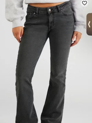 gråa bootcut jeans från Junkyard - Säljer ett par svarta bootcut jeans från Junkyard i storlek S. Jeansen har klassisk femficksdesign, knapp och dragkedja fram samt bälteshällor. Materialet är jeans med en mjuk känsla och passformen är normal med lite utsvängda ben.